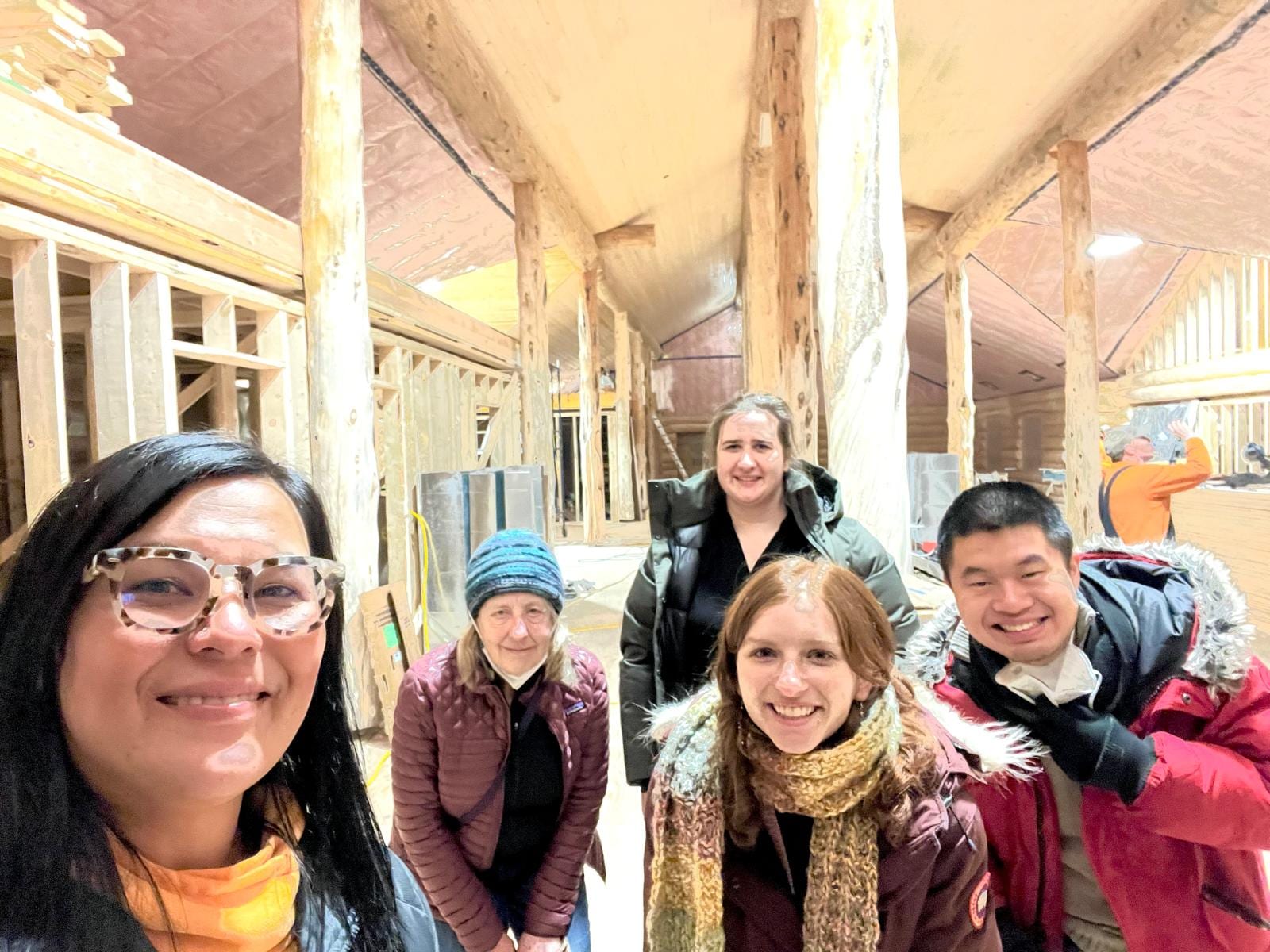 A field-visit team together inside a wood-framed building