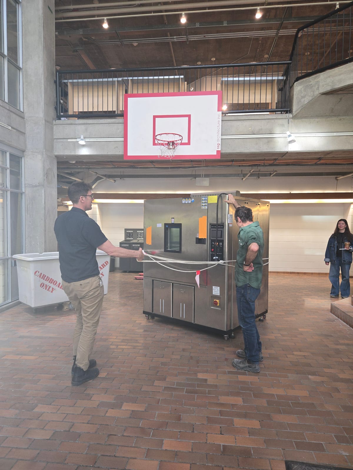 Two people moving an environmental test chamber