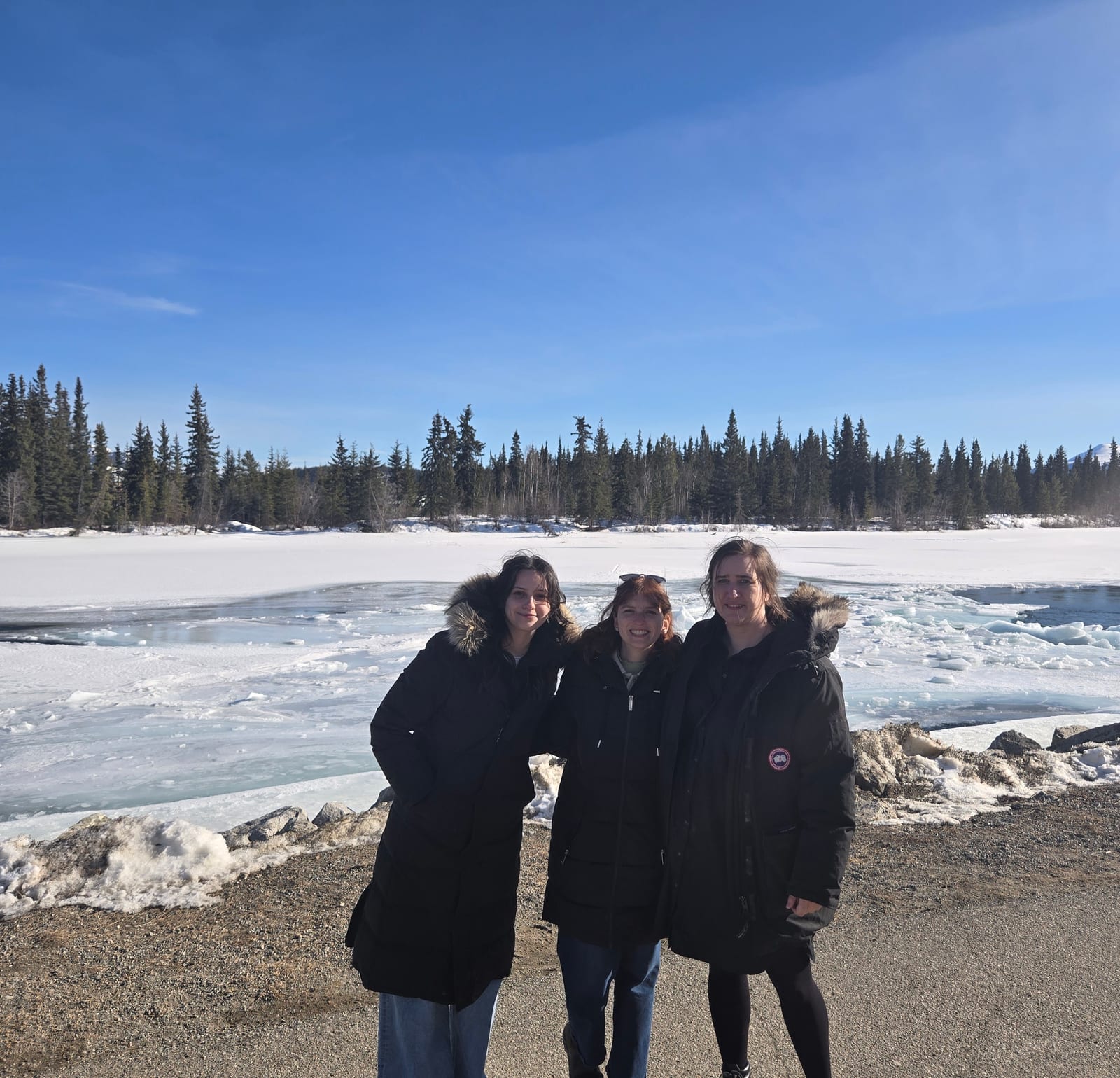 Three researchers beside a partly frozen northern lake